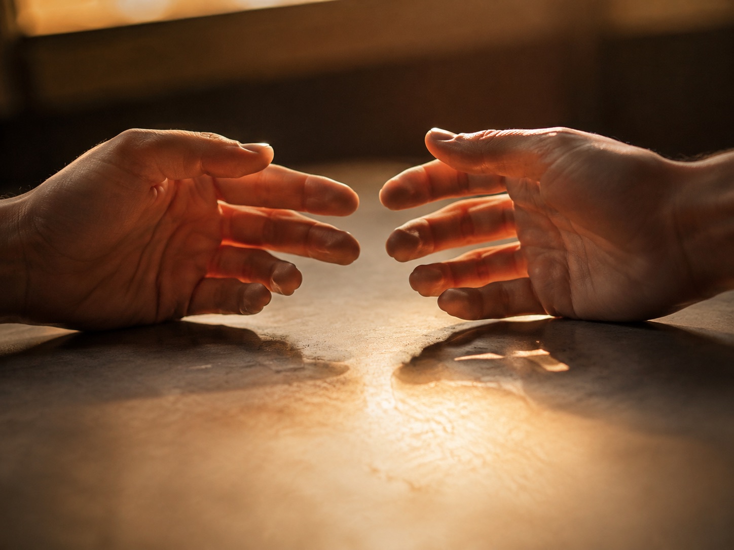 Two hands meeting in a soft light as an energetic interaction reference