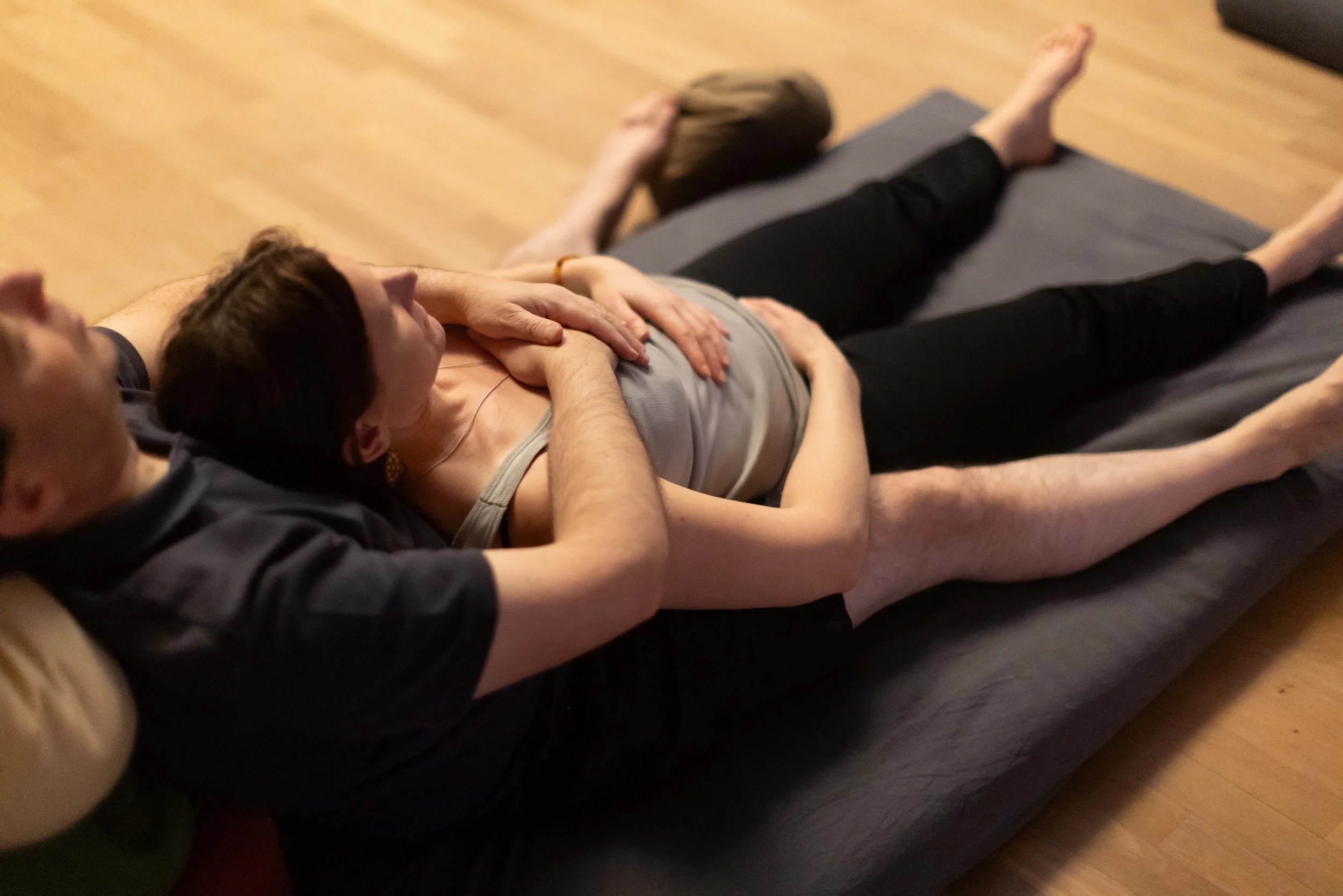 tantra approach — a man holding a woman in a safe, warm embrace on a practice mat